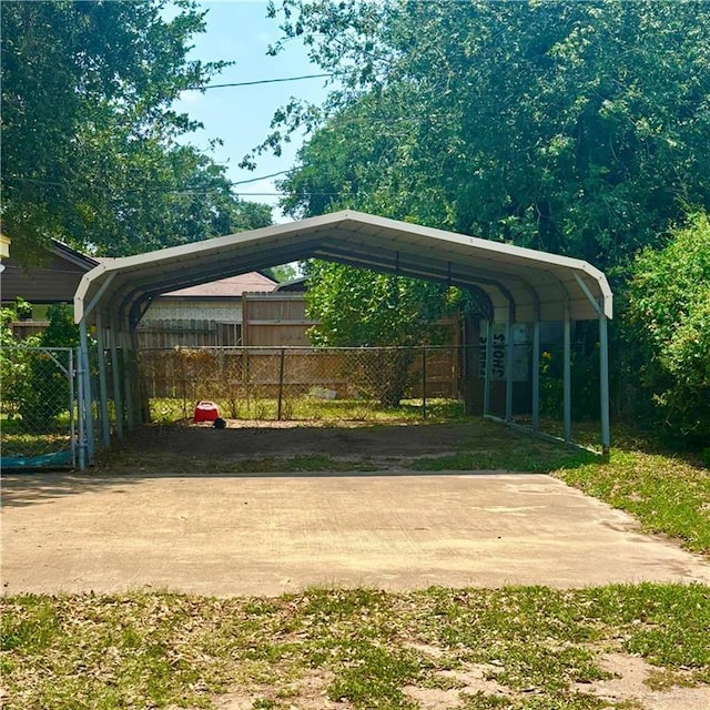 view of parking with fence and a detached carport