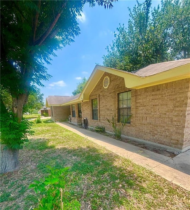 view of home's exterior with brick siding and a lawn