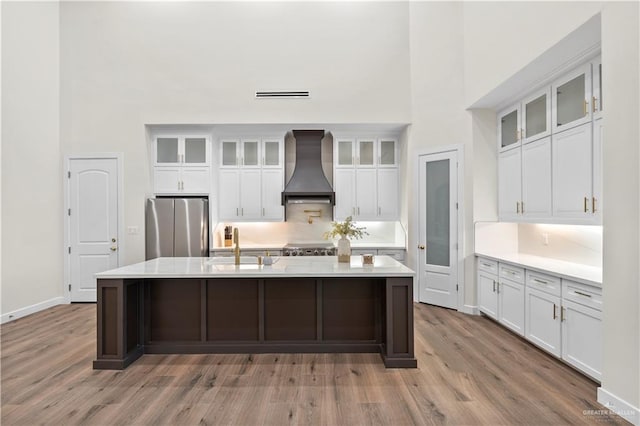 1620 Stonegate Dr, Mission, TX 78574 - kitchen with custom range hood, stainless steel appliances, light wood-type flooring, white cabinets, and light countertops