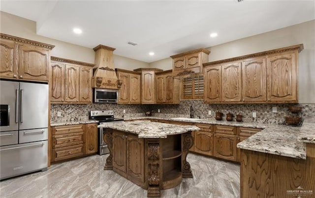 kitchen with a center island, backsplash, sink, light stone countertops, and stainless steel appliances