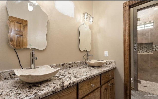 bathroom with toilet, vanity, and tiled shower