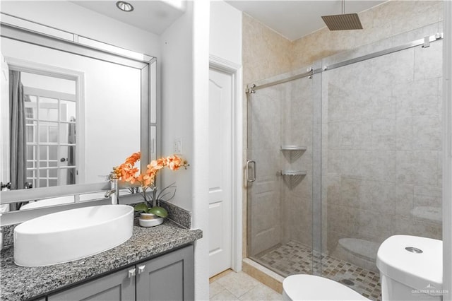 bathroom with toilet, vanity, tile patterned floors, and a shower with shower door