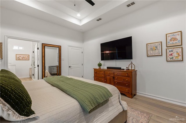 bedroom featuring connected bathroom, ceiling fan, and light wood-type flooring