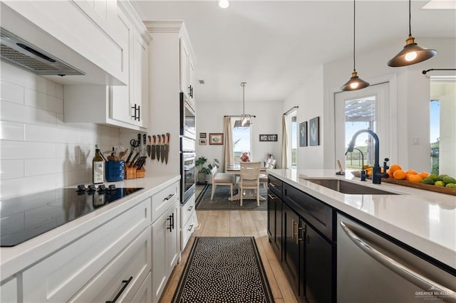 kitchen with sink, hanging light fixtures, extractor fan, white cabinets, and appliances with stainless steel finishes