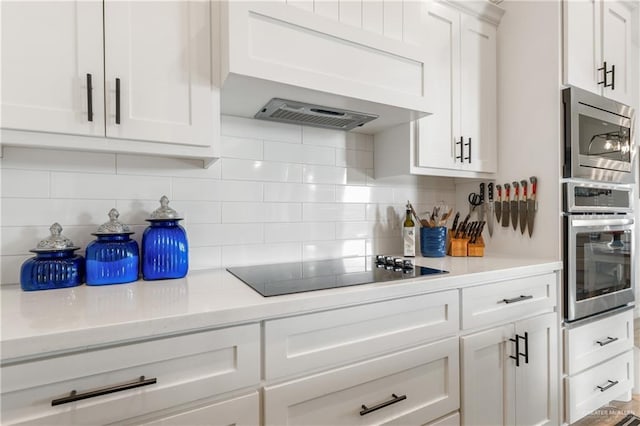 kitchen featuring white cabinets, decorative backsplash, stainless steel microwave, and black electric cooktop