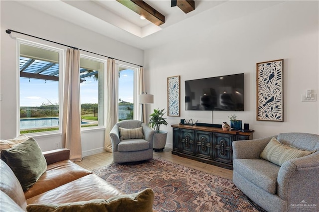 living room featuring beam ceiling, a wealth of natural light, a water view, and light wood-type flooring