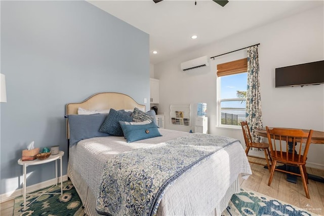 bedroom with light wood-type flooring, an AC wall unit, and ceiling fan