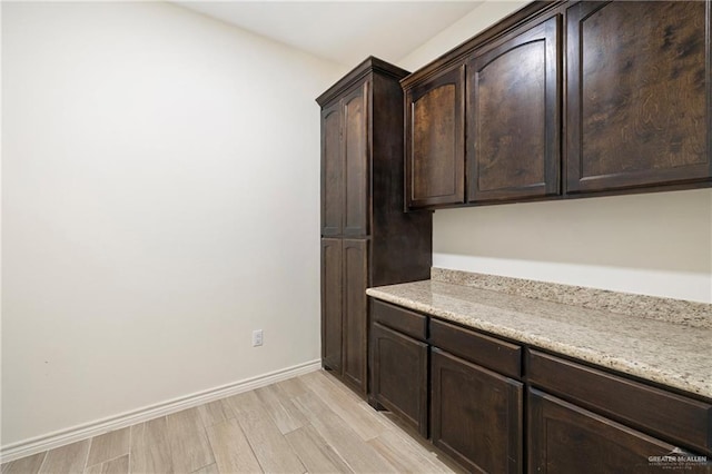 7303 Umar Ave, Mission, TX 78573 - kitchen featuring dark brown cabinetry, light wood finished floors, baseboards, and light stone counters