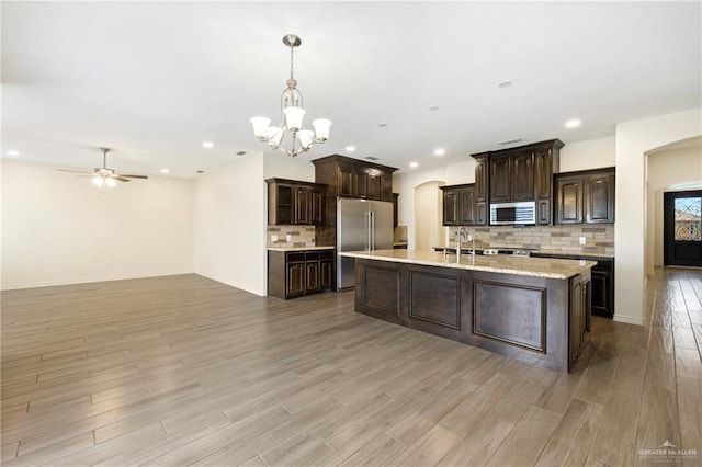 7303 Umar Ave, Mission, TX 78573 - kitchen featuring stainless steel appliances, arched walkways, dark brown cabinets, light wood-style flooring, and a chandelier