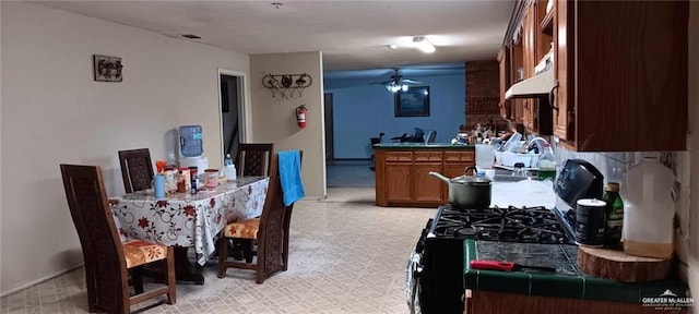 5906 N Brushline Rd, Mission, TX 78574 - kitchen featuring a ceiling fan, under cabinet range hood, brown cabinets, and baseboards
