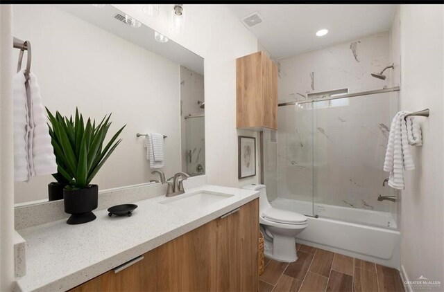 full bathroom featuring vanity, toilet, and shower / bath combination with glass door