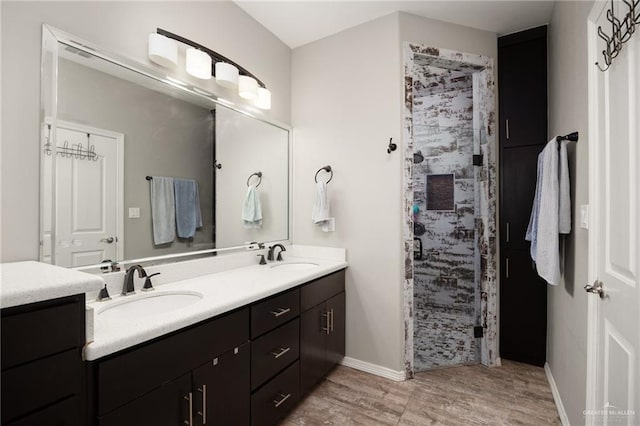 bathroom with hardwood / wood-style flooring, vanity, and a tile shower