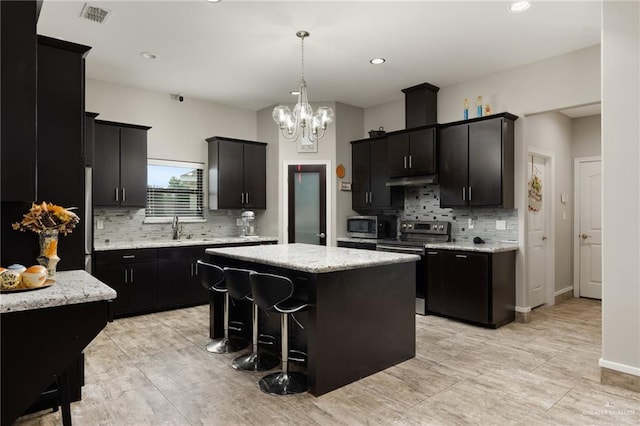 kitchen featuring backsplash, stainless steel appliances, sink, an inviting chandelier, and a kitchen island