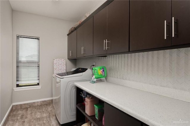 laundry room with cabinets, washing machine and dryer, and light hardwood / wood-style flooring