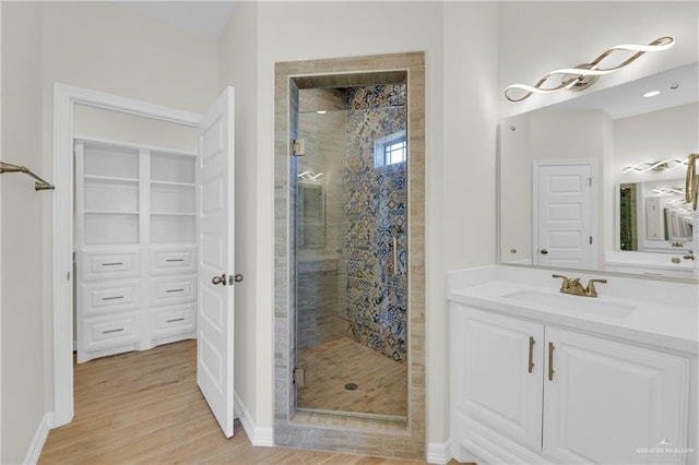 bathroom featuring hardwood / wood-style flooring, vanity, and walk in shower