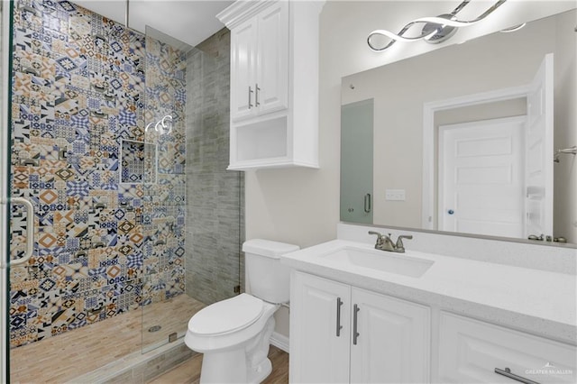 bathroom featuring hardwood / wood-style floors, vanity, a tile shower, and toilet