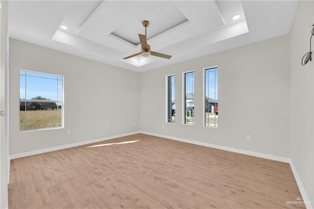 spare room featuring a raised ceiling, ceiling fan, and light hardwood / wood-style flooring