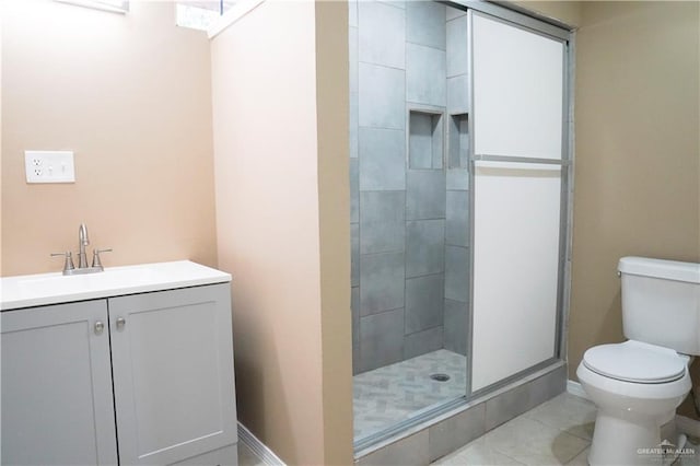 bathroom featuring a tile shower, tile patterned floors, vanity, and toilet