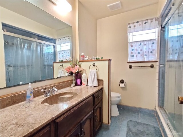 bathroom featuring tile patterned floors, plenty of natural light, walk in shower, and vanity