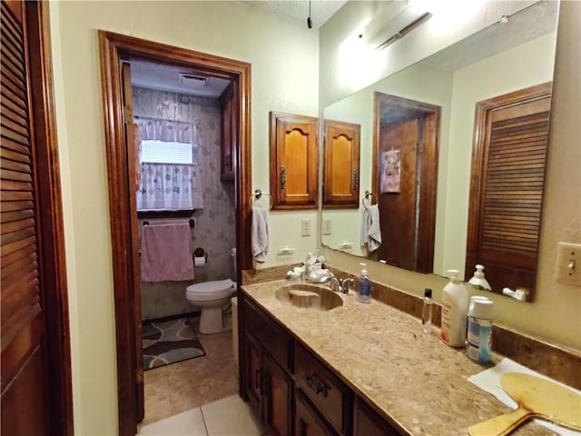 bathroom with tile patterned flooring, vanity, and toilet