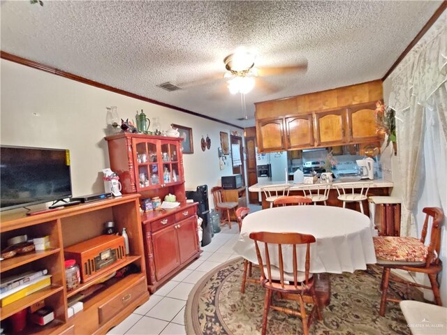 tiled dining area with a textured ceiling, ceiling fan, and crown molding