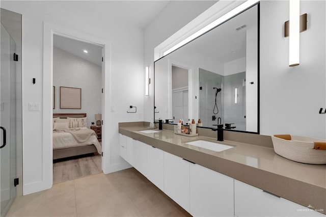 ensuite bathroom featuring tile patterned flooring, a sink, visible vents, a shower stall, and double vanity