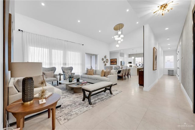 living area featuring a chandelier, baseboards, a towering ceiling, and recessed lighting