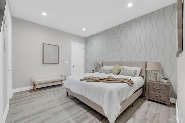 bedroom featuring an accent wall, recessed lighting, baseboards, and wood finished floors