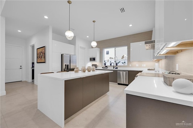 kitchen with modern cabinets, decorative light fixtures, stainless steel appliances, light countertops, and white cabinetry