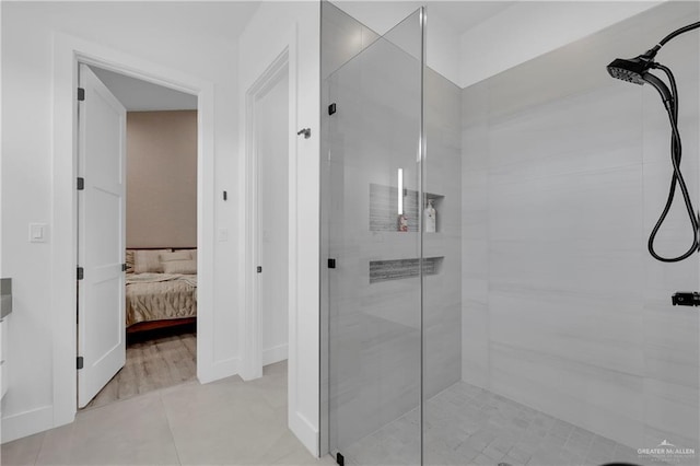 ensuite bathroom with ensuite bathroom, tile patterned flooring, a shower stall, and baseboards