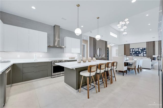 kitchen with appliances with stainless steel finishes, light countertops, wall chimney range hood, and modern cabinets