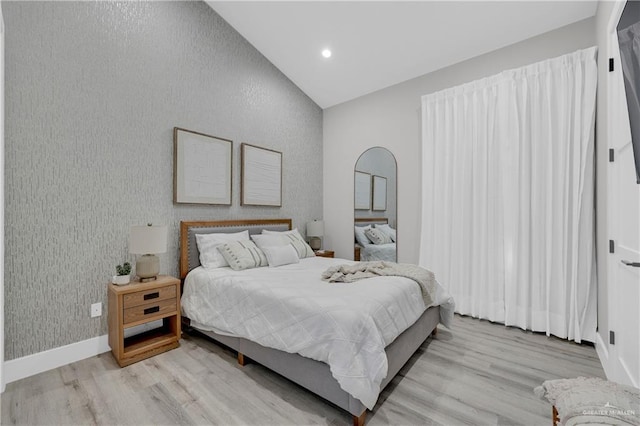 bedroom with lofted ceiling, wallpapered walls, light wood-type flooring, and baseboards