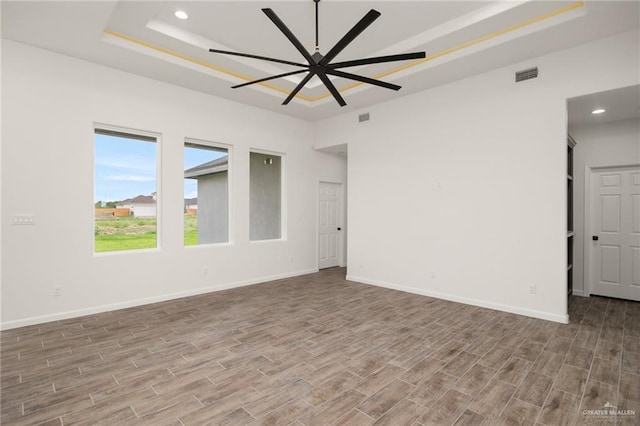 spare room featuring hardwood / wood-style flooring, ceiling fan, and a tray ceiling