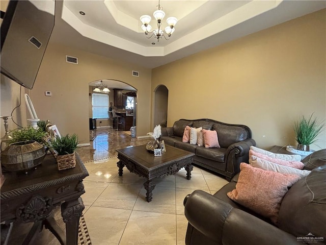 16400 Mcalister Ave, Edinburg, TX 78541 - living area featuring arched walkways, a chandelier, a tray ceiling, and light tile patterned floors
