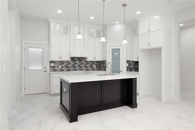 kitchen featuring marble finish floor, a sink, white cabinetry, and baseboards