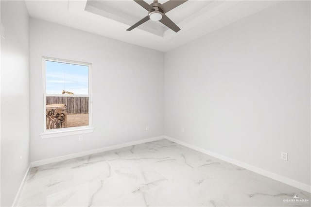 spare room featuring baseboards, ceiling fan, a tray ceiling, and marble finish floor