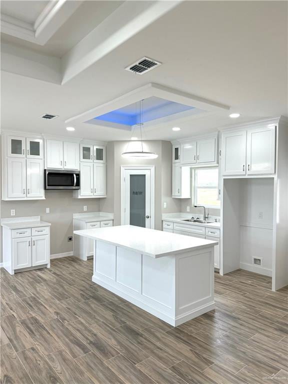 kitchen with white cabinetry, a tray ceiling, and a center island