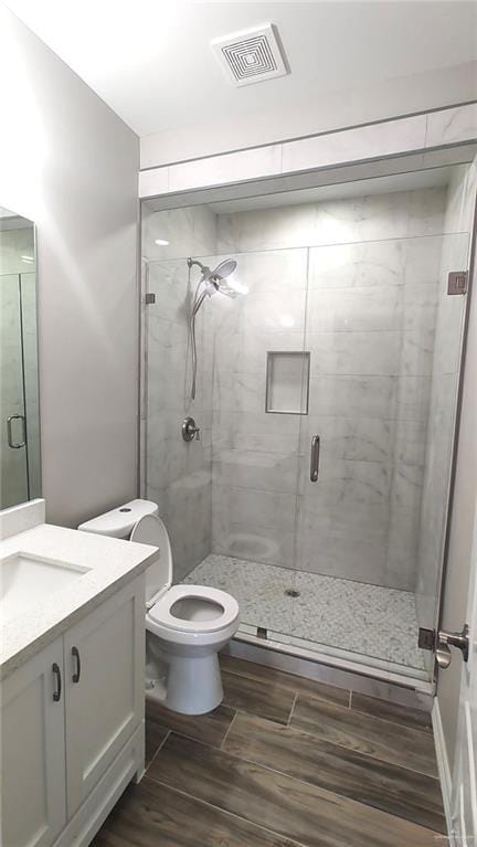 bathroom with vanity, toilet, and a shower with door