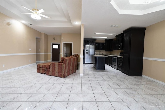 tiled living room with ceiling fan, a raised ceiling, and sink