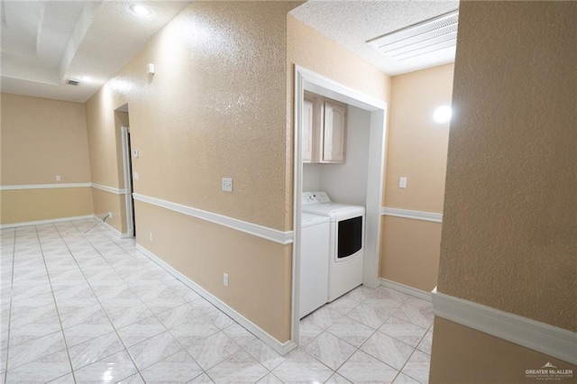 clothes washing area with cabinets and washing machine and dryer