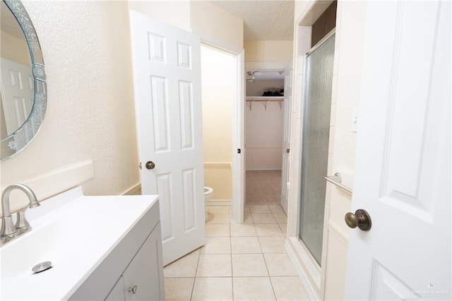 bathroom with vanity, toilet, tile patterned flooring, and a shower with door