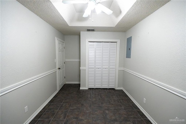 interior space with ceiling fan, a tray ceiling, and electric panel