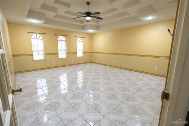 spare room featuring a raised ceiling and ceiling fan