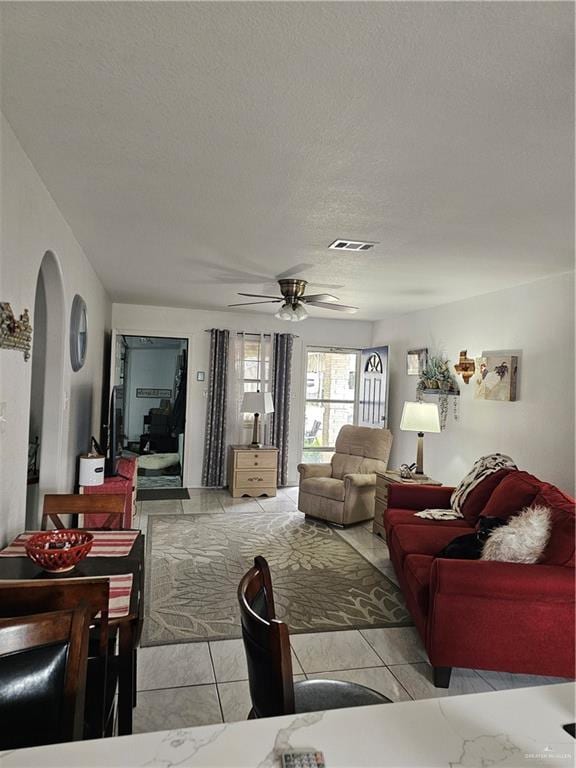 living room featuring ceiling fan and a textured ceiling