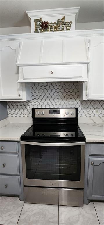 kitchen with white cabinets, gray cabinets, stainless steel range with electric cooktop, and light stone counters