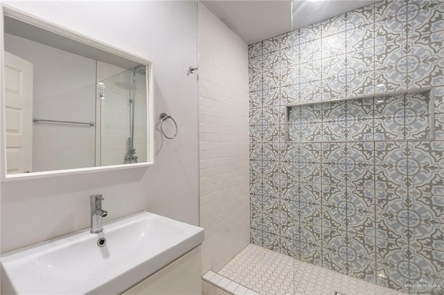 bathroom featuring tiled shower and vanity