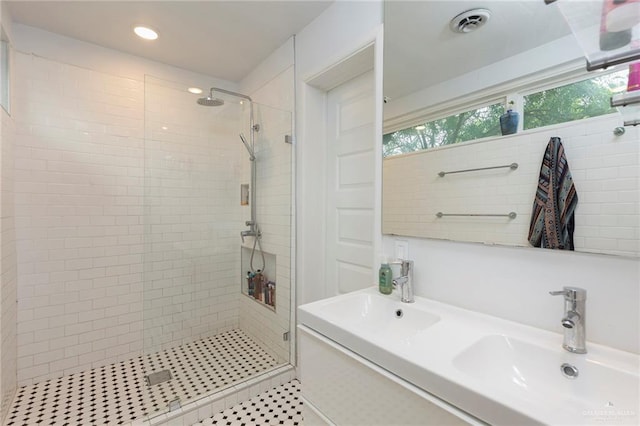 bathroom with double sink, tile patterned flooring, and a shower with shower door