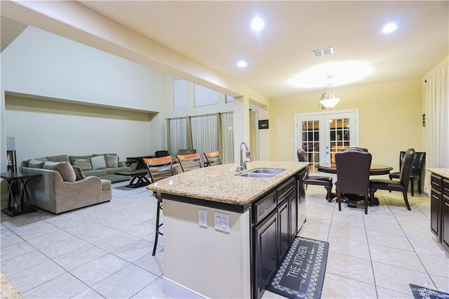 kitchen featuring dishwasher, a kitchen island with sink, french doors, a kitchen breakfast bar, and sink