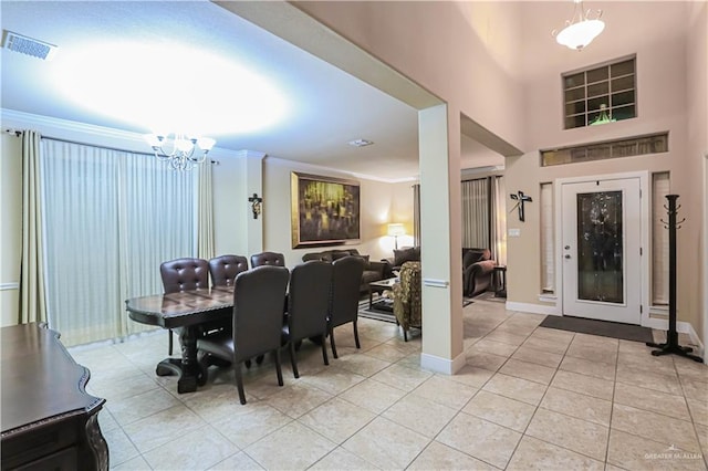 dining area with light tile patterned flooring, a towering ceiling, crown molding, and an inviting chandelier