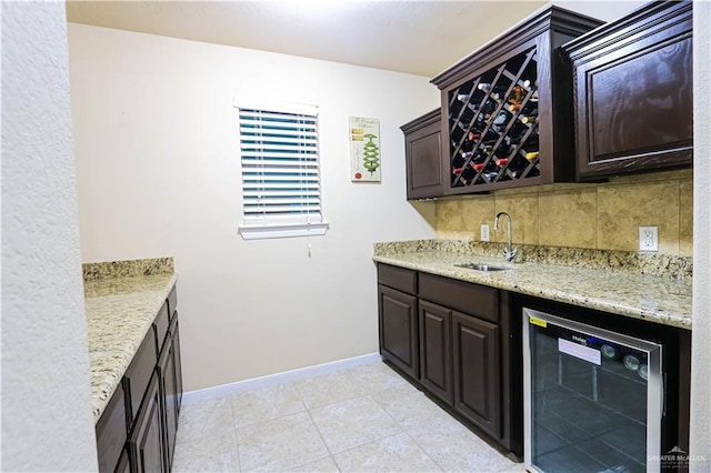 interior space with backsplash, light stone countertops, sink, and wine cooler